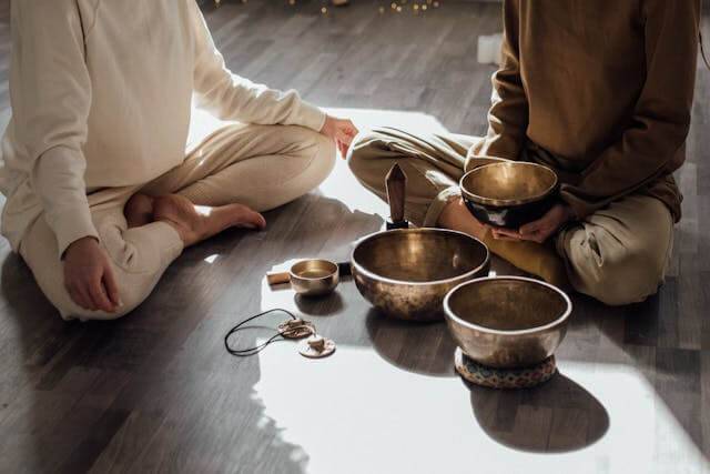 Two woman sitting on the floor doing a spiritual cleansing ritual.