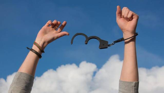 Spiritual healer breaking handcuffs off hands freeing them.