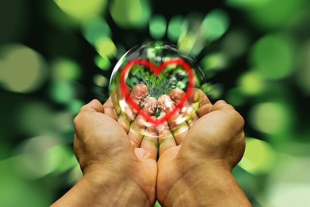 Hands holding a crystal ball with a heart in it representing how to heal your self spiritually.