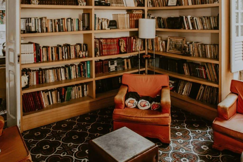 A clean library room with a orange couch giving an example of how to live more mindfully.