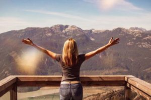 Woman standing on a wood overlook with her arms out who just did cord cutting spiritual healing services.