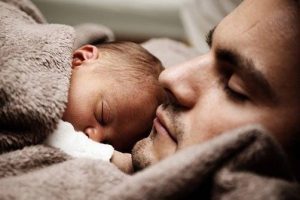 A man and his baby sleeping on his chest who just had the help stop insomnia spiritual healing service done.