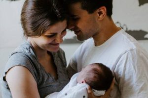 A happy couple holding a baby who had the help with fertility problems spiritual healing service done.