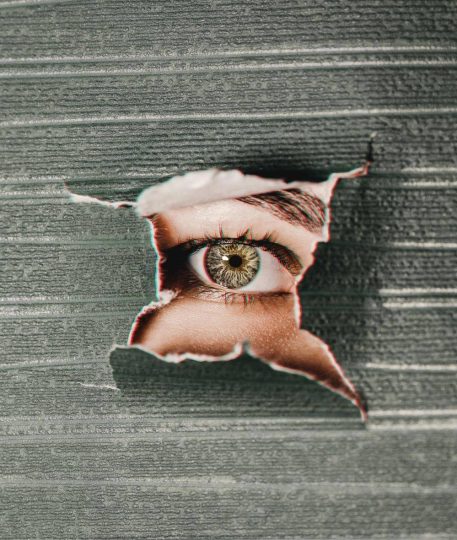 An eye looking through broken wallpaper having symptoms of evil eye.